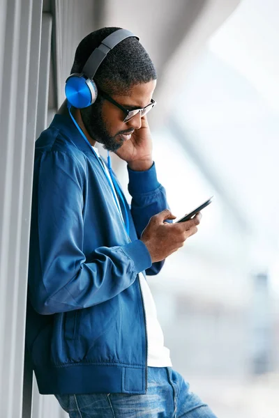 Muž poslech hudby ve sluchátkách na telefonu v ulici. — Stock fotografie