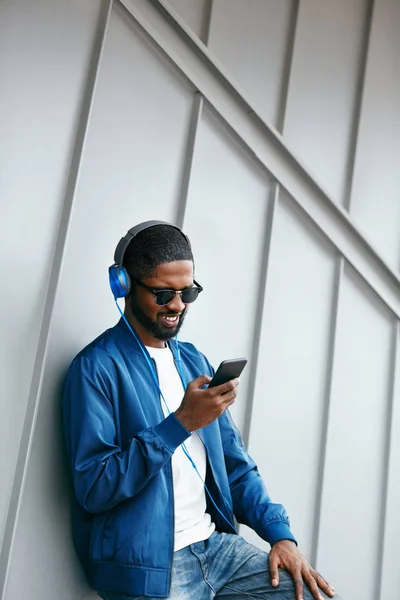 Mode und Musik. Mann mit Kopfhörer und Handy in der Stadt — Stockfoto