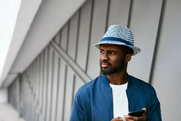 Schöner schwarzer Mann in modischer Kleidung mit Handy auf der Straße — Stockfoto