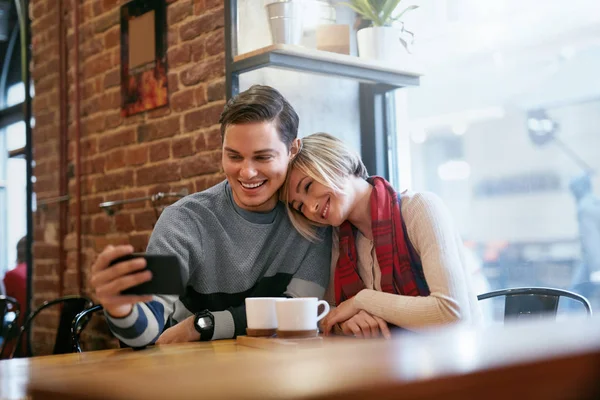 Pár používat na telefonu v Cafe pro Video volání nebo fotografování — Stock fotografie