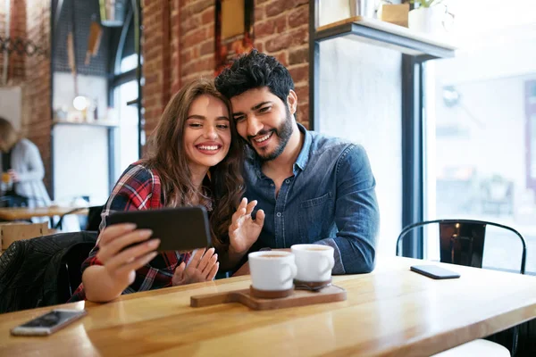 Pasangan Menggunakan On Phone In Cafe Untuk Memanggil Video Atau Mengambil Foto — Stok Foto