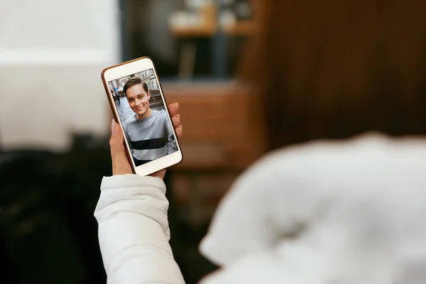 Chamada de vídeo no telefone. Fechar a mão com telefone e rosto na tela — Fotografia de Stock