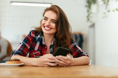 Mutlu kadın telefonu kafede kullanarak