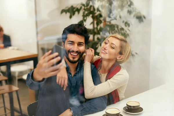 Szczęśliwi ludzie przy użyciu telefonu w Cafe, biorąc Zdjęcia — Zdjęcie stockowe