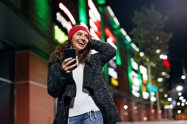 Happy Woman With Phone On Street In Evening. Beautiful Girl In Fashion Clothes Using Smartphone Outdoors. High Resolution