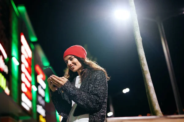 Šťastná žena s telefonem na ulici večer — Stock fotografie