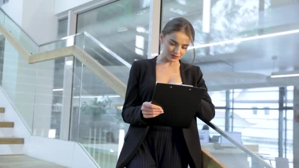 Mujer de negocios con carpeta en las manos en el edificio de oficinas — Vídeos de Stock