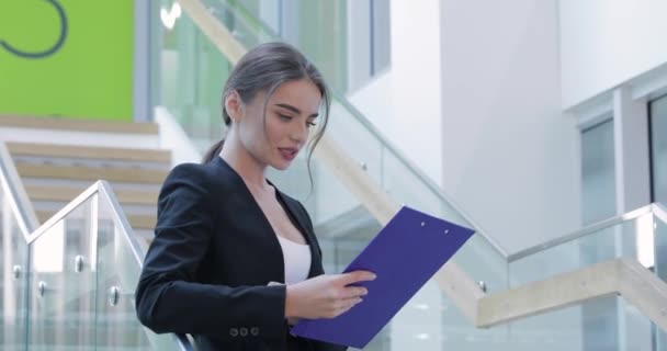 Mujer de negocios con carpeta en las manos en el edificio de oficinas — Vídeos de Stock