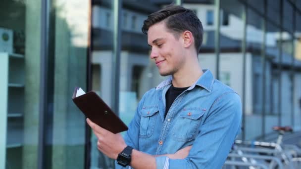 Hombre estudiante lectura bloc de notas al aire libre en la universidad — Vídeos de Stock