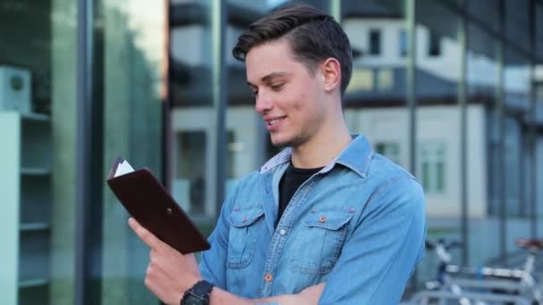 Männlicher Student liest Notizblock im Freien an der Hochschule — Stockvideo