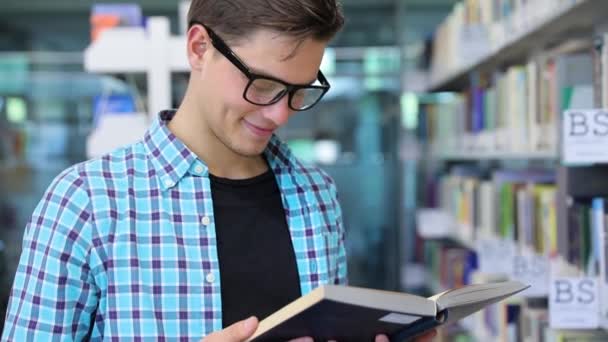 Estudante na biblioteca leitura de livros perto de estantes — Vídeo de Stock