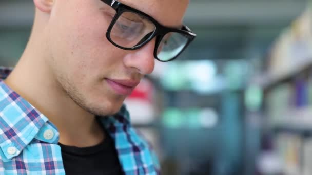 Toko buku. Man Student Reading Books Near Bookshelves — Stok Video