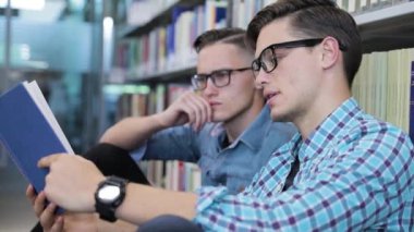 Öğrenciler Üniversite kütüphanesinin raflardan kitap okuma