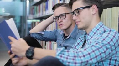 Öğrenciler Üniversite kütüphanesinin raflardan kitap okuma