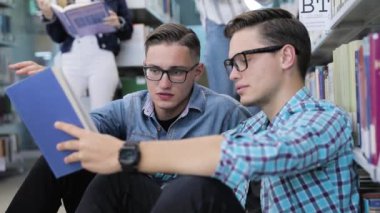 Öğrenciler Üniversite kütüphanesinin raflardan kitap okuma