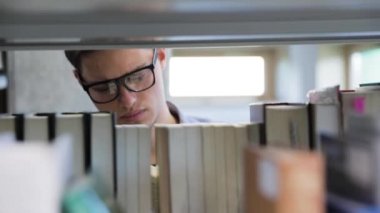 Kolej kütüphane. Erkek öğrenci raflardan kitap arama