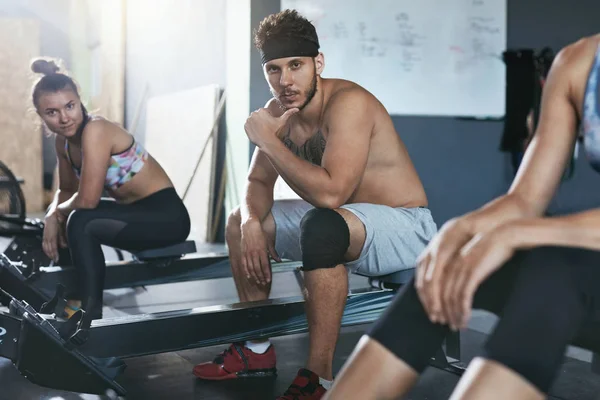 Crossfit. Gente haciendo ejercicio en la máquina de remo en el gimnasio de entrenamiento — Foto de Stock