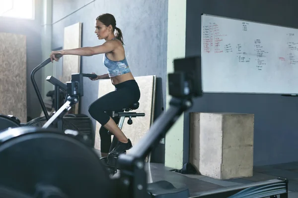 Sport im Fitnessstudio. Frauentraining auf Crossfit-Fahrrad — Stockfoto
