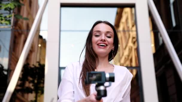 Відеоблогінг. Жінка з камерою біля сучасної будівлі бізнесу — стокове відео