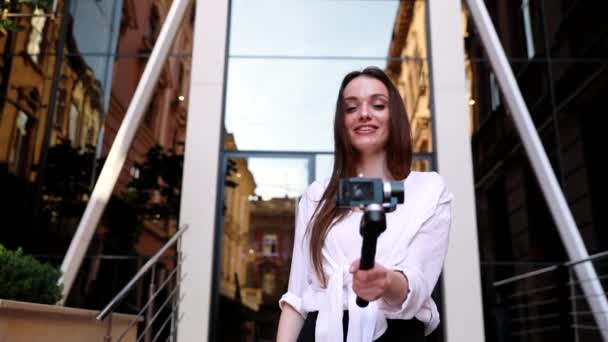 Videoblogga. Kvinna med kameran nära Modern Business Building — Stockvideo