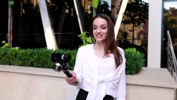 Жінка знімає відео на камеру біля сучасної будівлі офісу — стокове відео