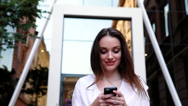 Mujer usando teléfono móvil en la calle cerca del edificio de oficinas — Vídeos de Stock