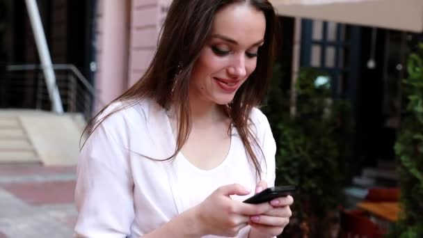 Vrouw met behulp van mobiele telefoon op straat in de buurt van kantoorgebouw — Stockvideo