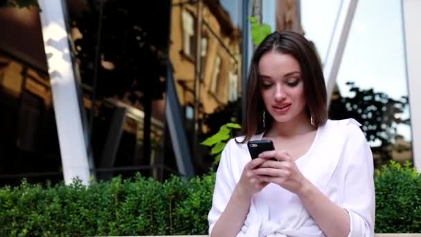 Mujer usando teléfono móvil en la calle cerca del edificio de oficinas — Vídeos de Stock