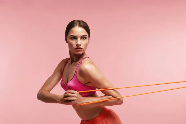 Treino. Mulher treinando com bandas de resistência em fundo rosa — Fotografia de Stock