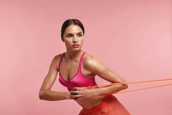 Treino. Mulher treinando com bandas de resistência em fundo rosa — Fotografia de Stock