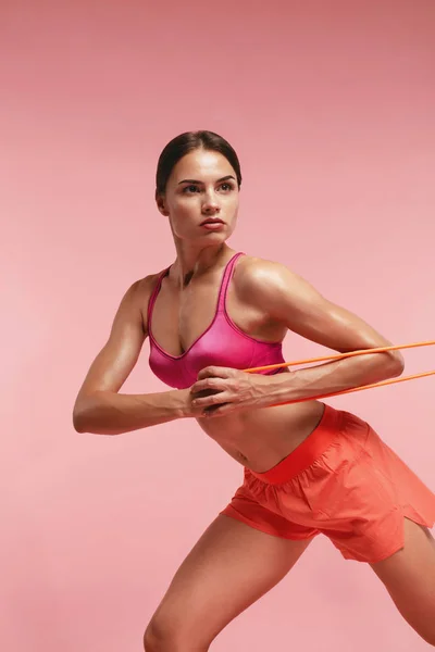 Treino. Mulher treinando com bandas de resistência em fundo rosa — Fotografia de Stock