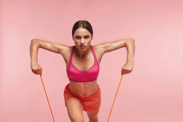Träning. Kvinna träning med motstånd band på rosa bakgrund — Stockfoto