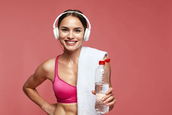 Wasser trinken. Sportlerin mit Kopfhörer und Flasche in der Hand — Stockfoto