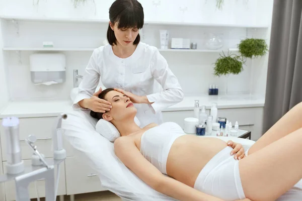 Masaż skóry twarzy. Kobieta w ciąży w klinice kosmetologii — Zdjęcie stockowe