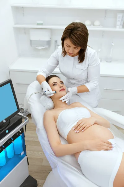 Cuidado de la piel. Embarazada mujer en cara limpieza en belleza clínica —  Fotos de Stock