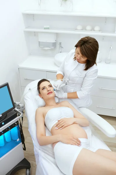 Cuidado de la piel. Embarazada mujer en cara limpieza en belleza clínica —  Fotos de Stock