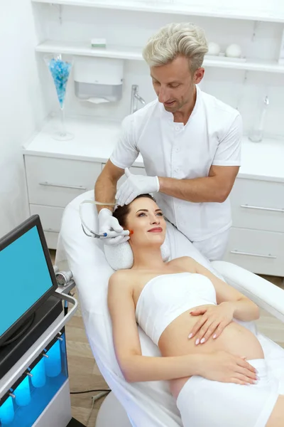 Беременная женщина проходит лечение лица в косметологической клинике — стоковое фото