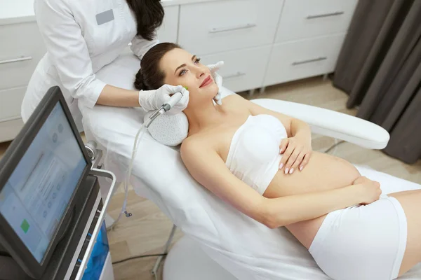 В клинике красоты. Беременная женщина проводит интенсивное пилинговое лечение — стоковое фото