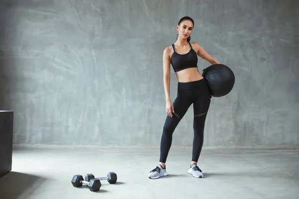 Mujer deportiva en negro entrenamiento de ropa deportiva con pelota de fitness — Foto de Stock
