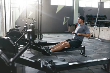 Fonksiyonel eğitim. Kürek makine spor salonunda egzersiz yapan erkek