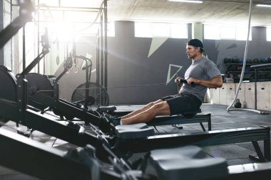 Fonksiyonel eğitim. Kürek makine spor salonunda egzersiz yapan erkek