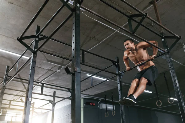 Entrenamiento. Hombre deportivo haciendo ejercicio Pull Ups en el rack deportivo — Foto de Stock