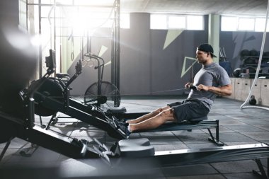 Kardiyo egzersizi. Kürek makine spor salonunda egzersiz spor adamı