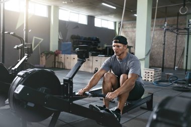Kardiyo egzersizi. Kürek makine spor salonunda egzersiz spor adamı