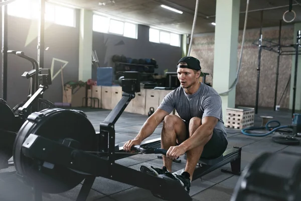 Entrenamiento cardiovascular. Hombre deportivo haciendo ejercicio en la máquina de remo en el gimnasio — Foto de Stock