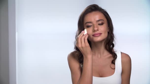 Maquillaje. Hermosa mujer aplicando la fundación en la cara con esponja — Vídeo de stock