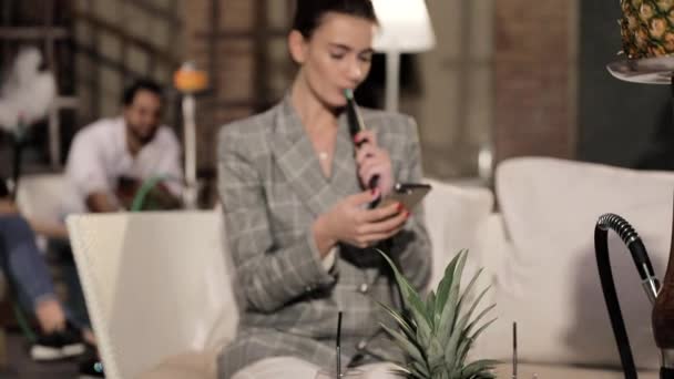 Donna fumare narghilè e utilizzando il telefono a Shisha Lounge — Video Stock