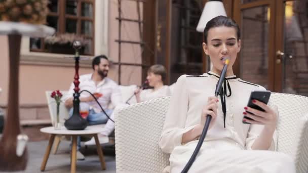 Bar Hookah. Mujer fumando Shisha y usando el teléfono móvil — Vídeos de Stock