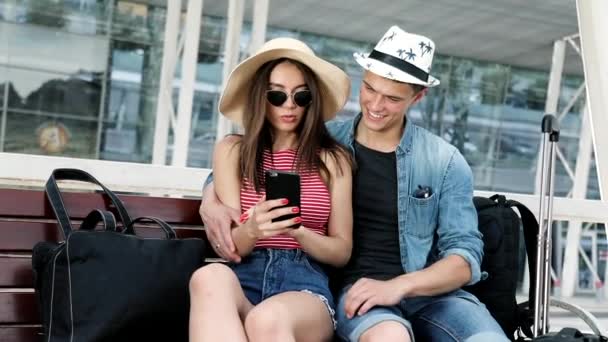 Viajar. casal usando telefone, esperando transporte perto do aeroporto — Vídeo de Stock