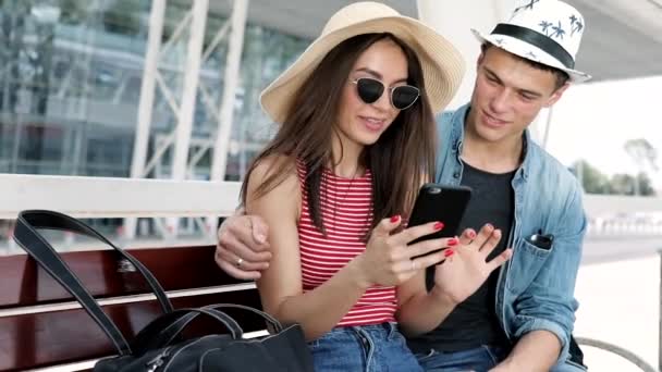 Viajar. casal usando telefone, esperando transporte perto do aeroporto — Vídeo de Stock